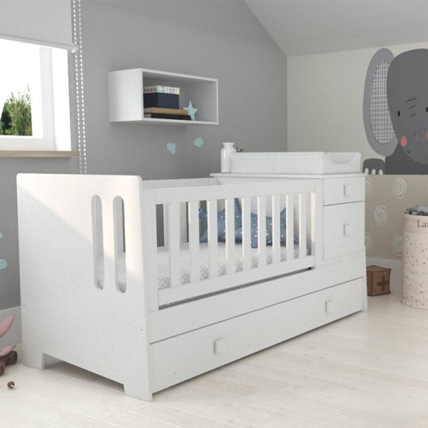 Cuna funcional modelo Frida de madera color blanco, con baranda lateral, cajonera incorporada de dos cajones y carro cama inferior, sobre fondo blanco con sombras técnicas.