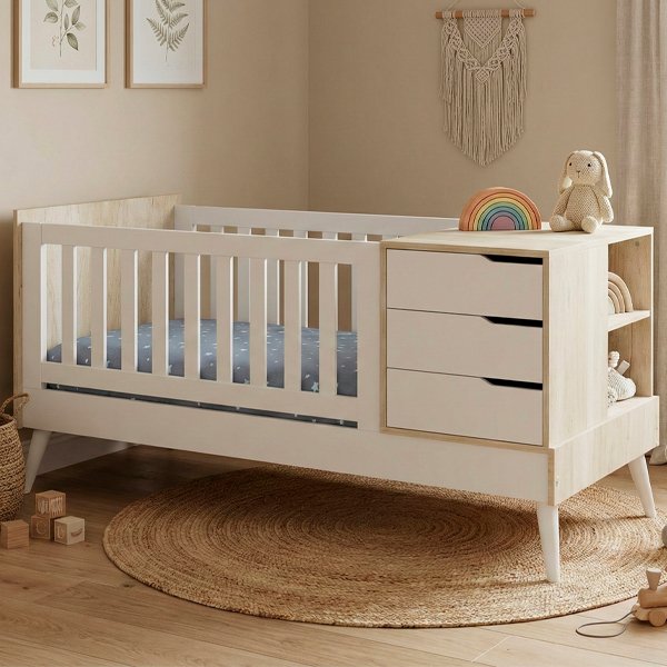 Cuna funcional modelo Neo de estilo nórdico en color blanco y madera clara, con cajonera integrada de tres niveles y estantes laterales sobre base de patas cónicas.
