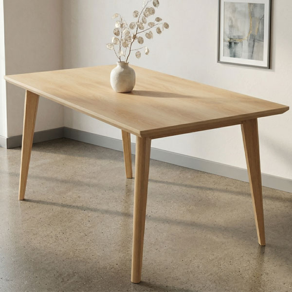 Mesa de comedor modelo Moss fabricada en madera clara de guatambú, con diseño nórdico y patas inclinadas, ambientada en un comedor minimalista con luz natural y piso de cemento.