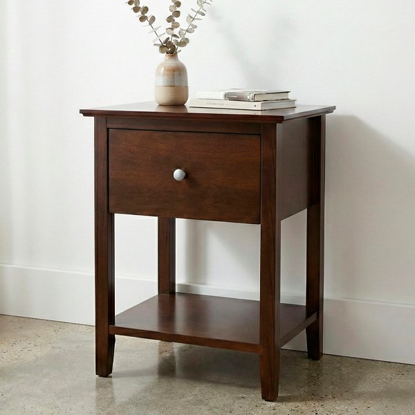 Mesa de luz SW de madera color tabaco con un cajón, tirador metálico circular y estante inferior, sobre fondo neutro con iluminación de estudio.