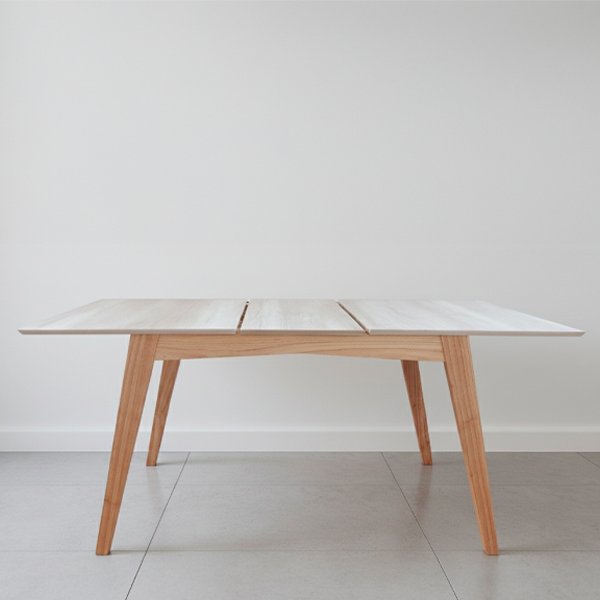 Mesa de comedor extensible modelo Andrea con patas de madera maciza de paraíso y tapa de MDF enchapada en melamina color Helsinki sobre un fondo blanco minimalista.