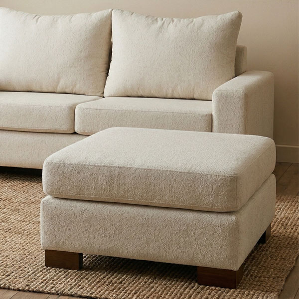 Puff Osiris cuadrado de 70x70x45 cm tapizado en tela beige de textura suave con patas de madera oscura, mostrado sobre fondo blanco técnico.