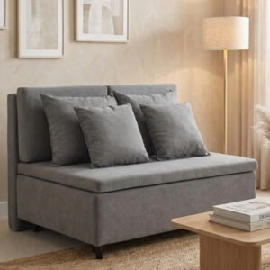 Sofá cama compacto modelo Horizon tapizado en tela color gris, ambientado en un living de tonos neutros con luz natural, alfombra de fibras naturales y decoración sutil.