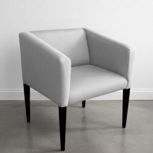 Sillón Bona tapizado en tela gris Tucson con patas de madera negra sobre piso de cemento alisado