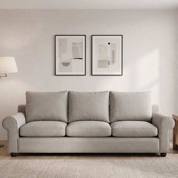 Sillón de 3 cuerpos tapizado en tela de color gris oscuro, ubicado sobre una alfombra tejida en un acogedor ambiente de sala de estar.