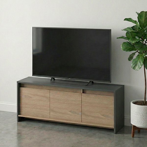 Mueble rack para TV de diseño moderno con estructura gris oscuro y tres puertas de madera clara, ubicado en una sala con pared blanca, zócalo clásico y piso de cemento alisado. Una televisión de pantalla plana está centrada sobre el mueble y una lámpara de pie decora el lateral.