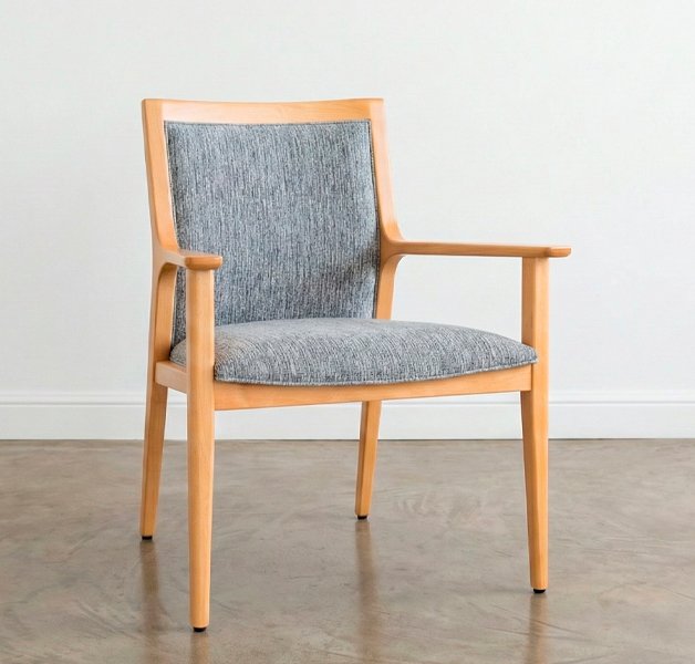 Sillón Olsen Classic de madera clara con respaldo y asiento tapizados en tela gris texturizada sobre un piso de cemento alisado.