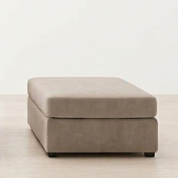 Vista frontal de un puff rectangular Elix de 80 cm tapizado en terciopelo taupe, sobre un suelo de madera clara contra una pared blanca.